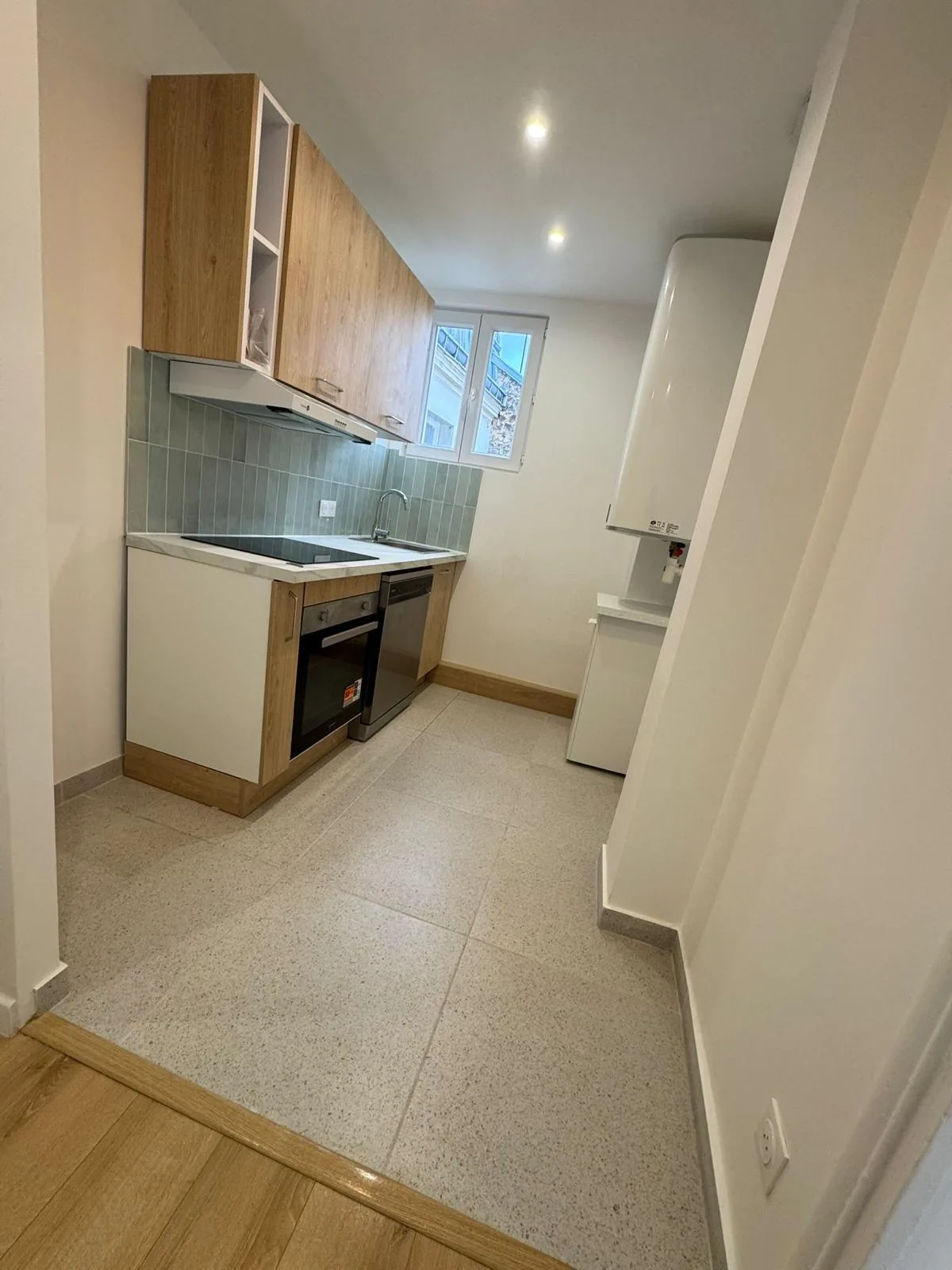 Cuisine équipée neuve installée par CK Bâtiment dans un appartement rénové à Saint-Denis, crédence vert d'eau et sol grès cérame