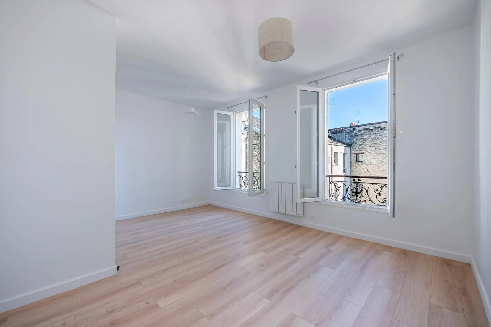 Séjour rénové par CK Bâtiment dans un appartement de Saint-Denis : parquet clair, murs blancs et fenêtres remises en état