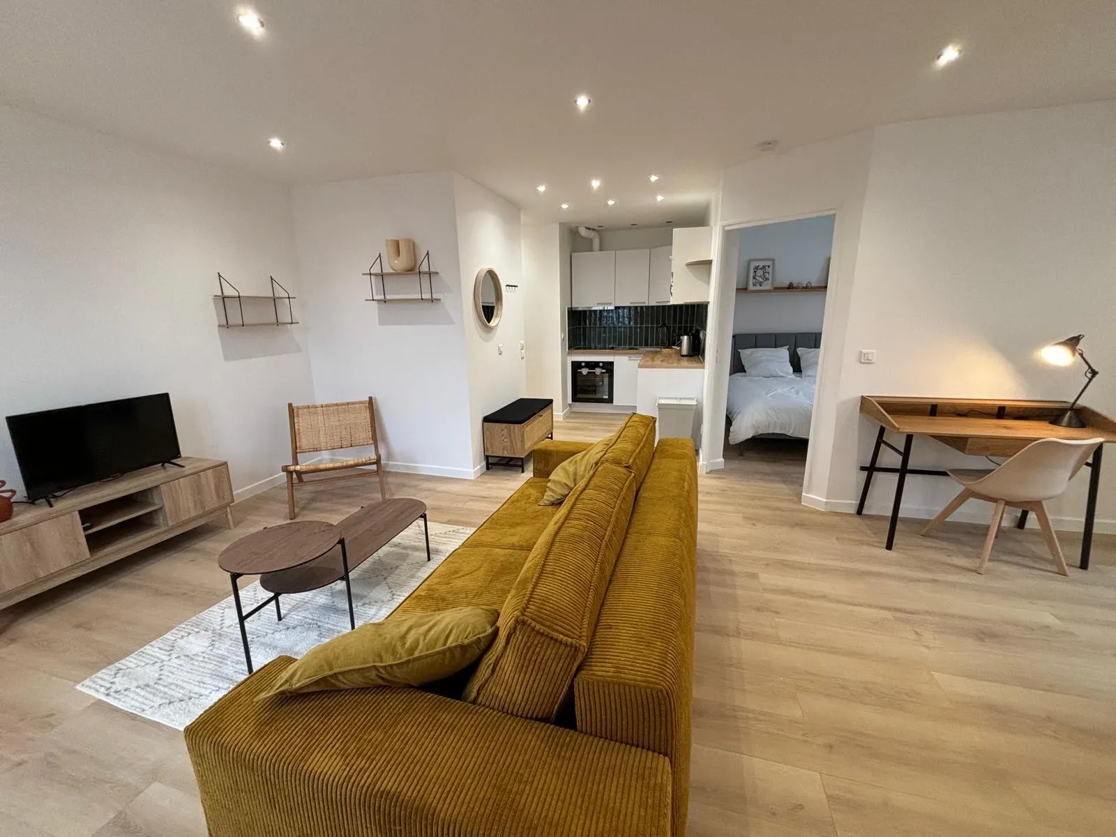 Appartement rénové à Saint-Denis par CK Bâtiment : séjour ouvert sur cuisine et chambre, parquet clair et murs blancs après rénovation complète