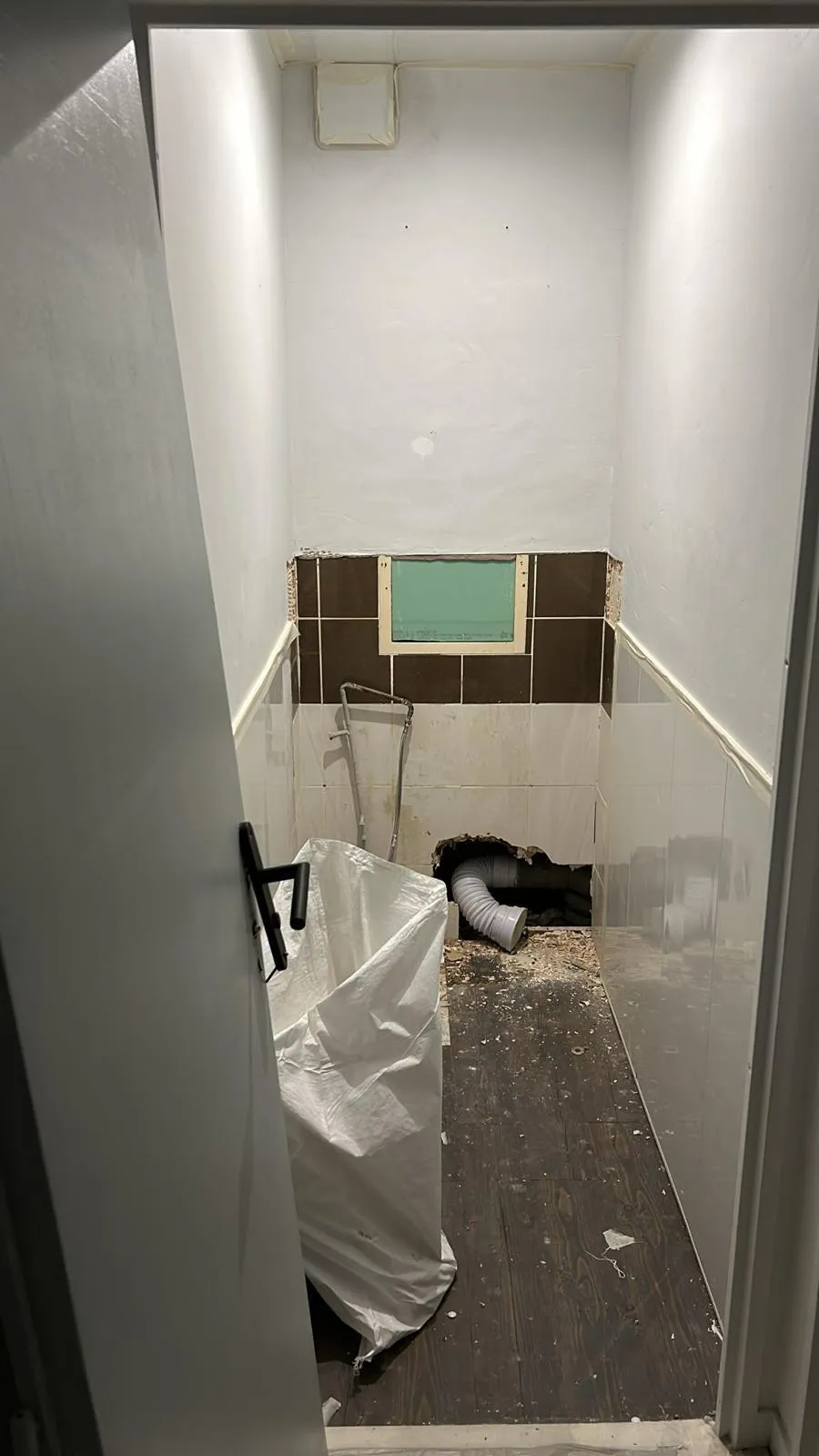 Avant travaux : sanitaires démolis à Creil, sol brut et évacuation apparente